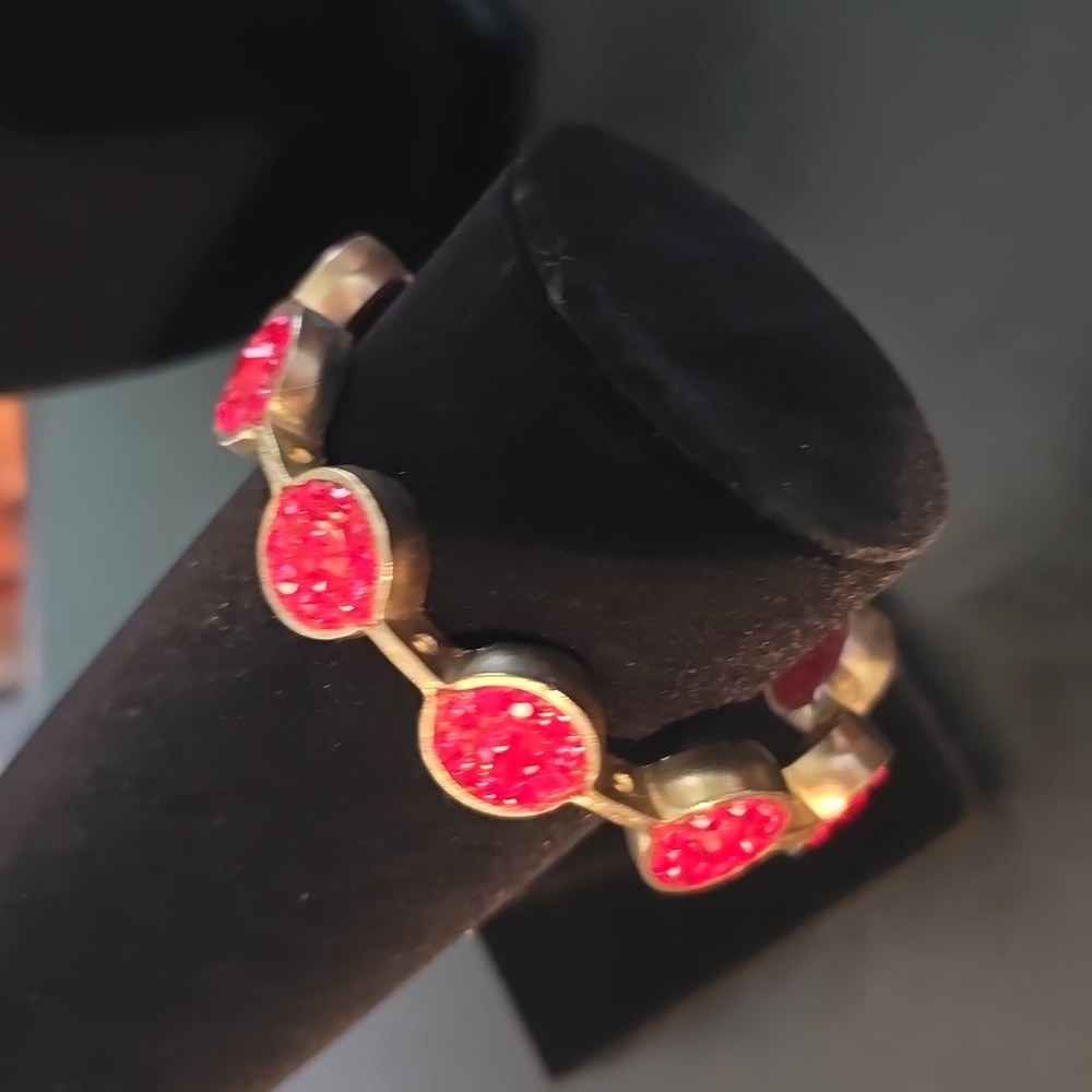Gold tone bangle bracelet with red crystals.